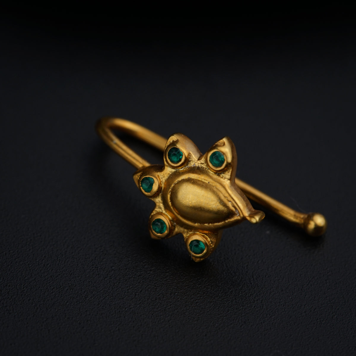 a close up of a gold ring with green stones