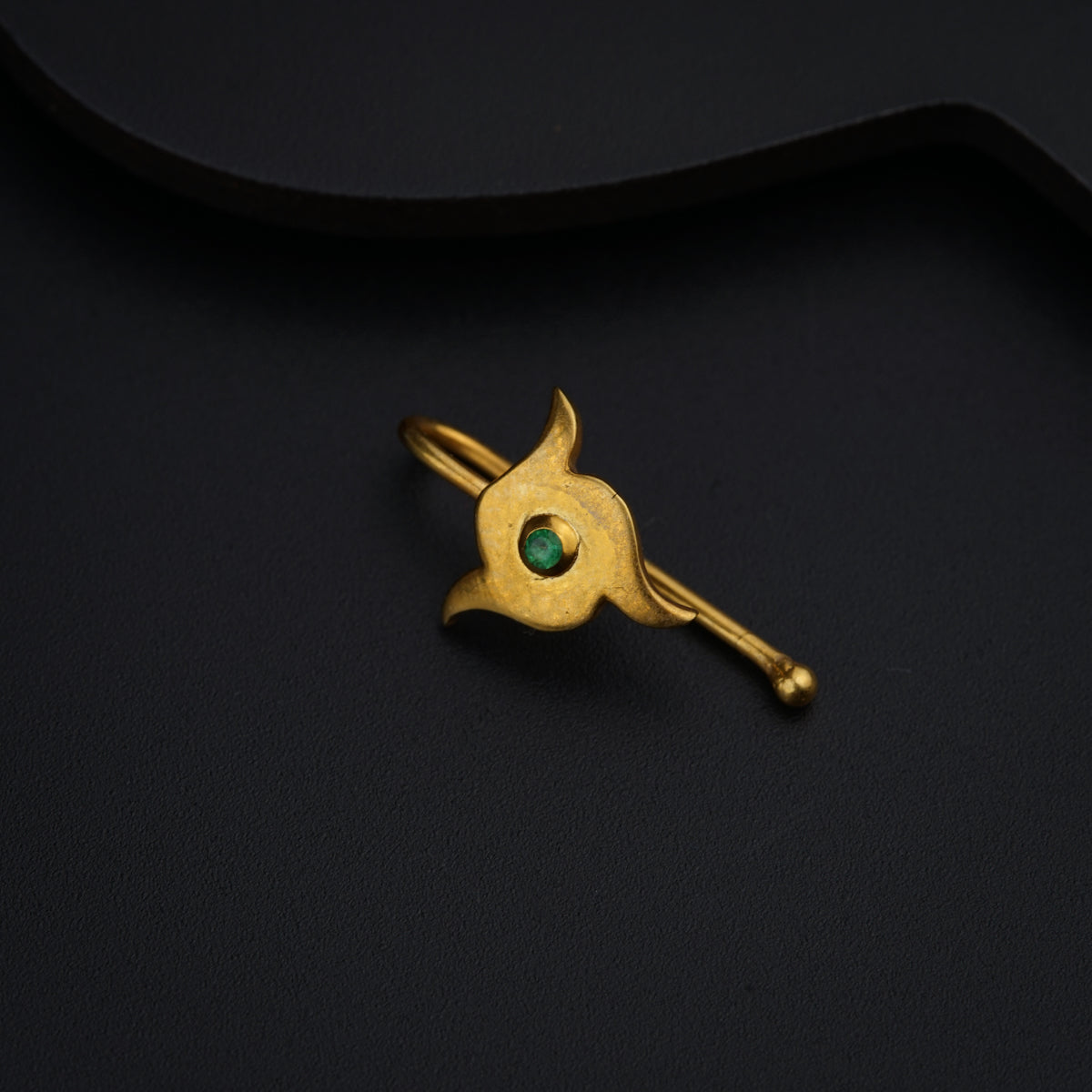 a gold brooch with a green stone on it