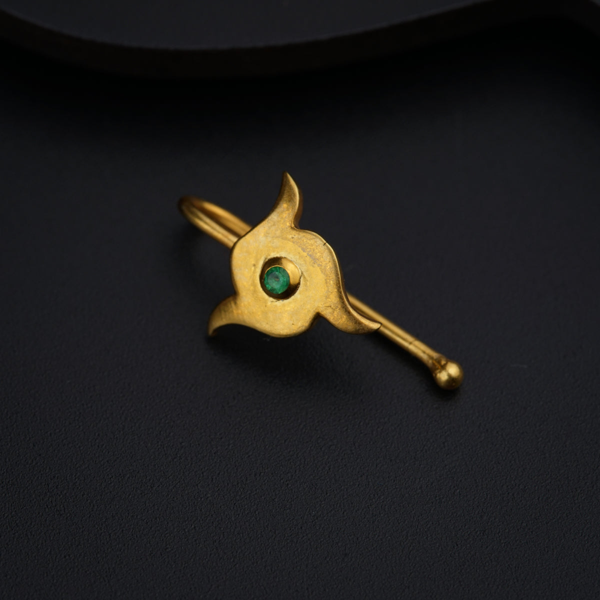 a gold brooch with a green stone in the middle
