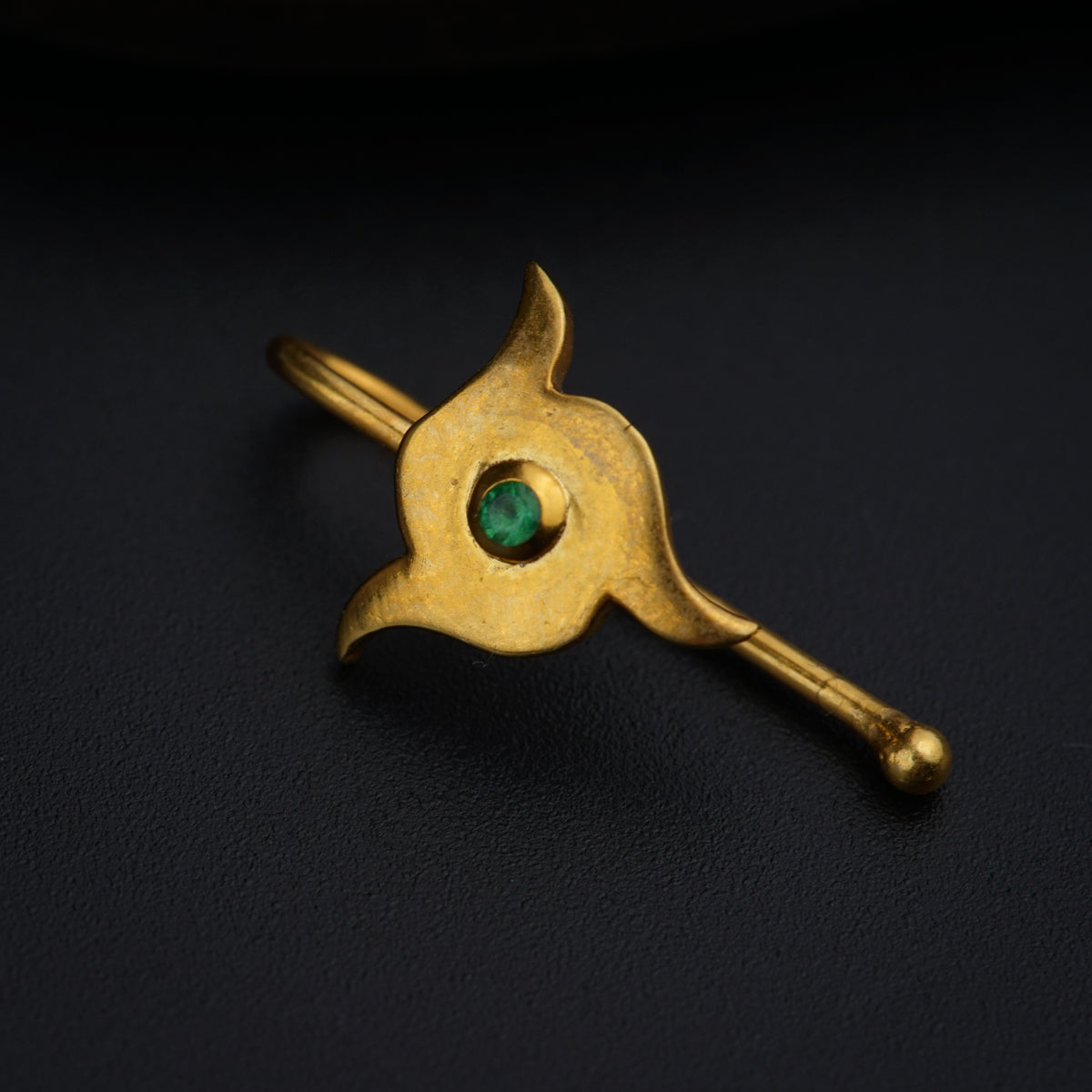 a gold brooch with a green stone in the center