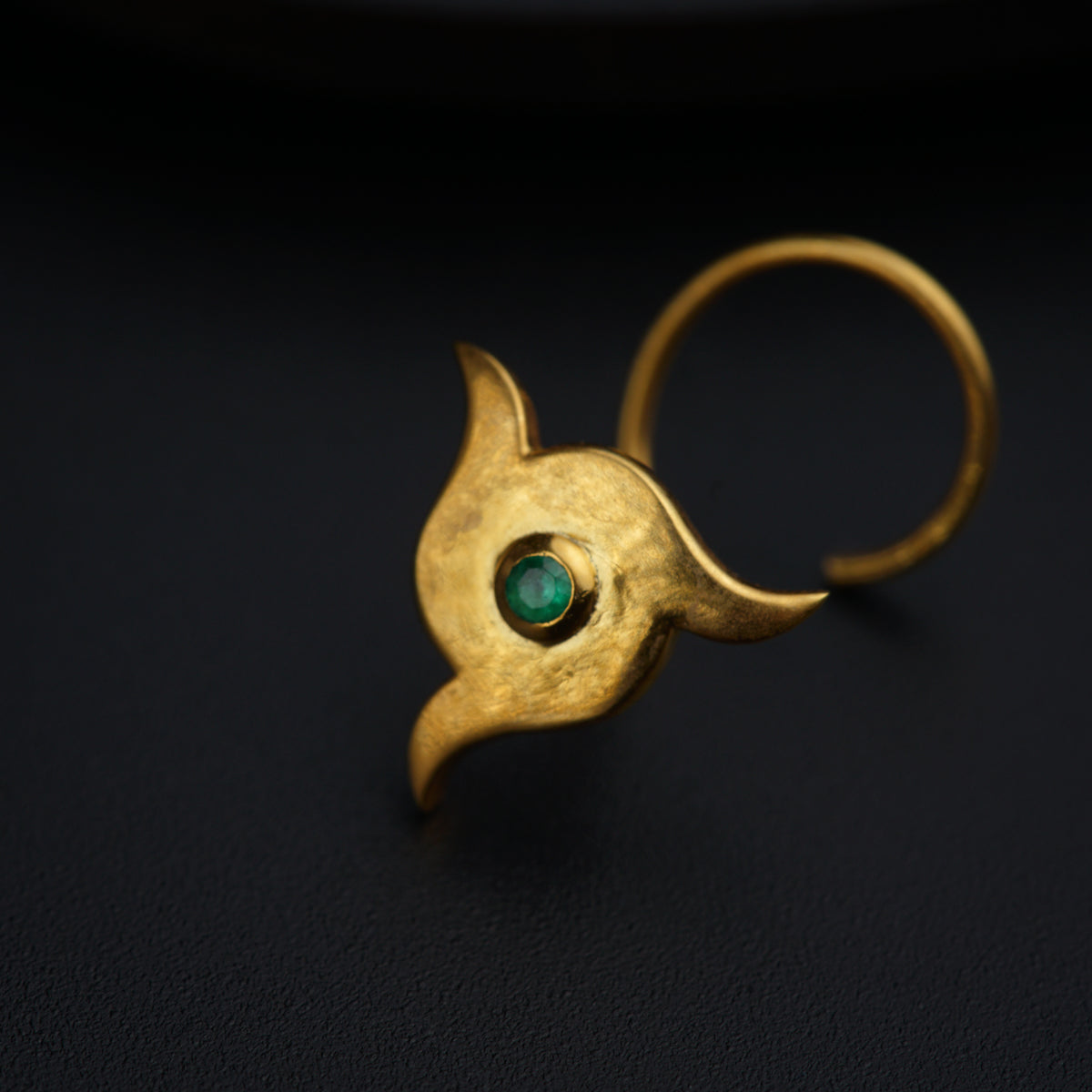 a close up of a gold ring with a green stone