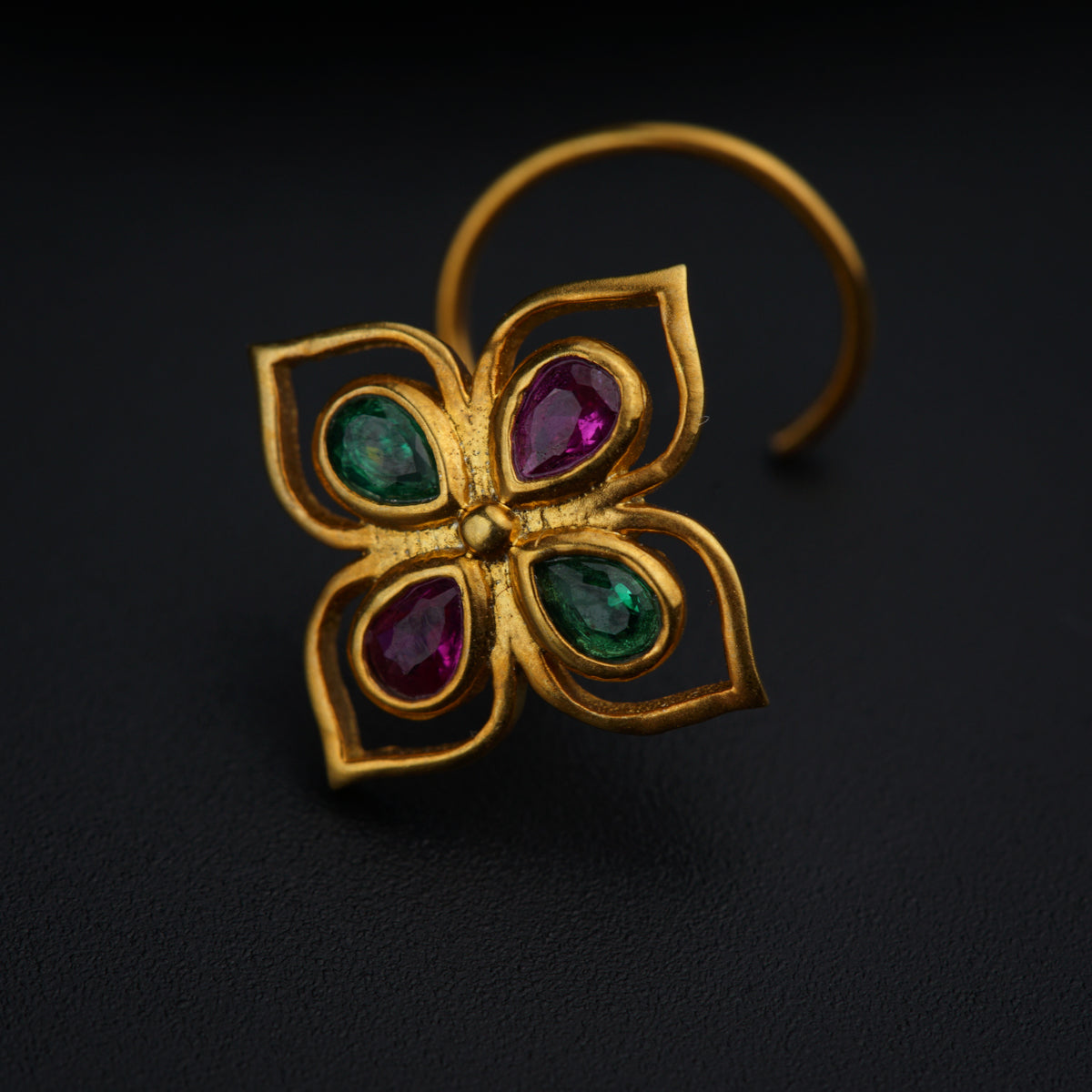 a close up of a gold ring with green and red stones