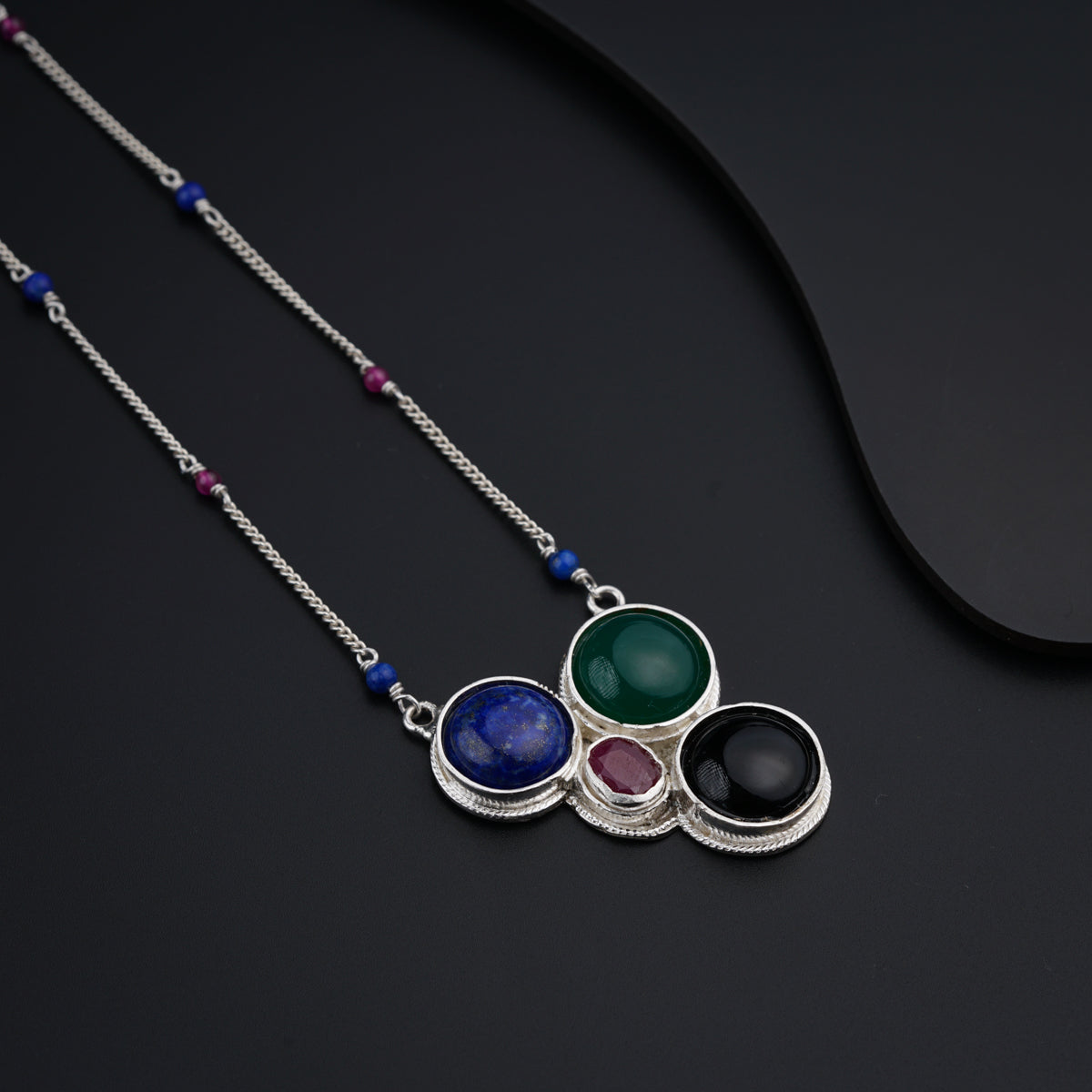 a necklace with three different colored stones on it