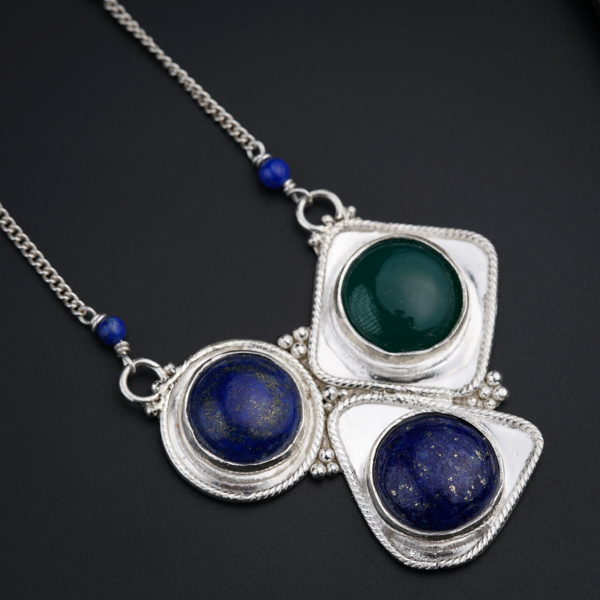 three pendants with blue and green beads on a black surface