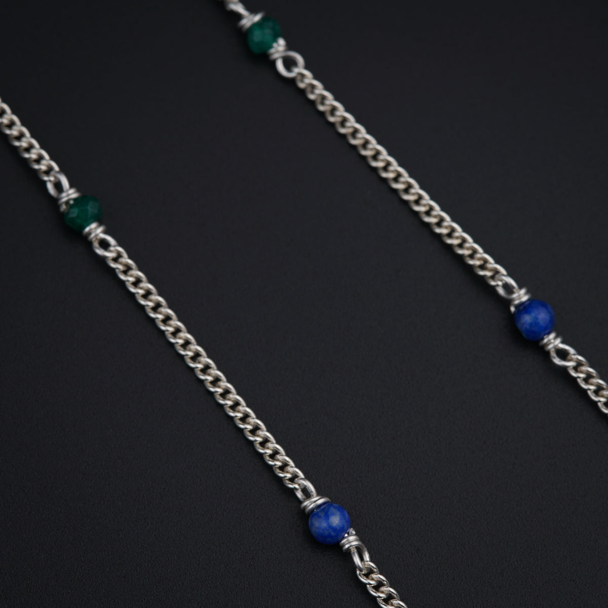 a close up of a chain with a blue bead on it