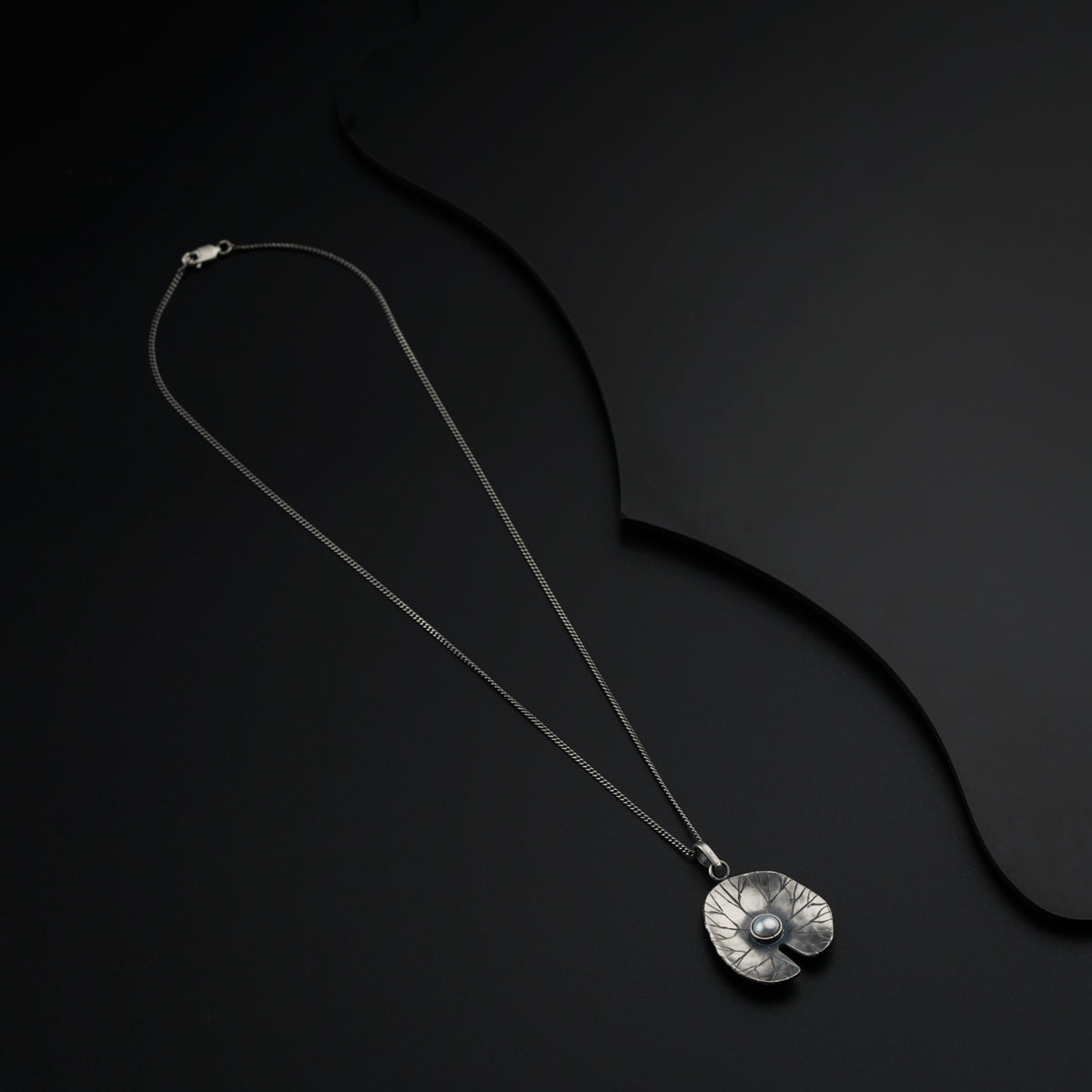 a necklace with a silver pendant on a black background