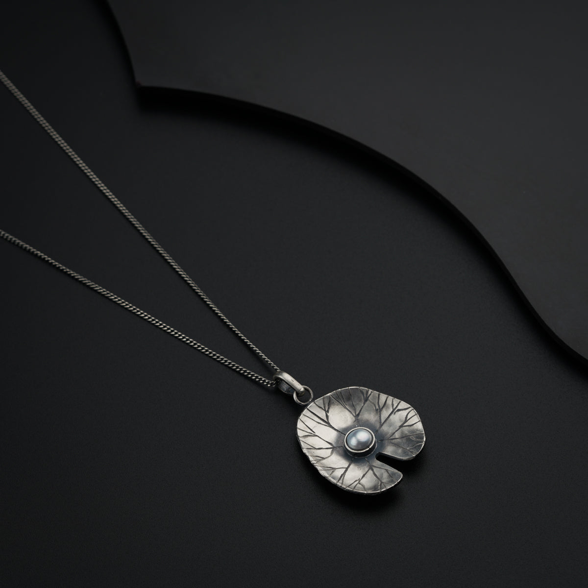 a silver necklace with a pearl in the center
