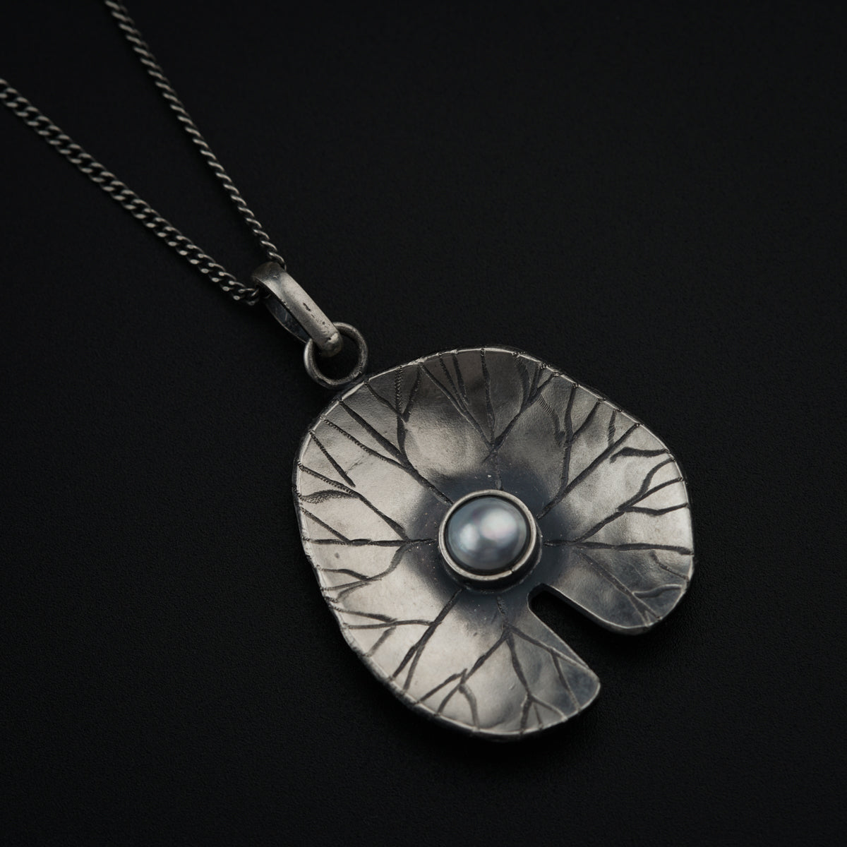 a silver pendant with a pearl in the center