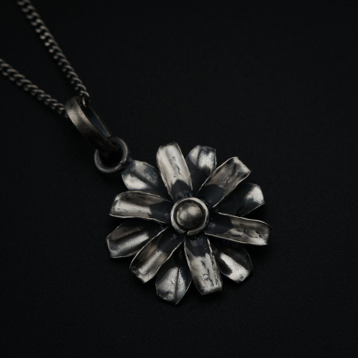 a silver flower pendant on a black background