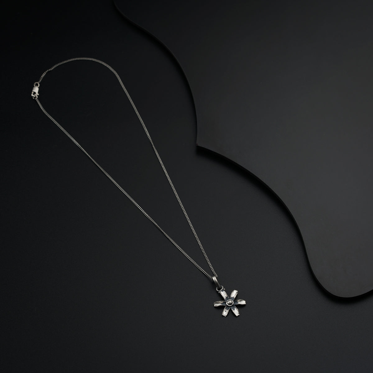 a necklace with a flower on a black background