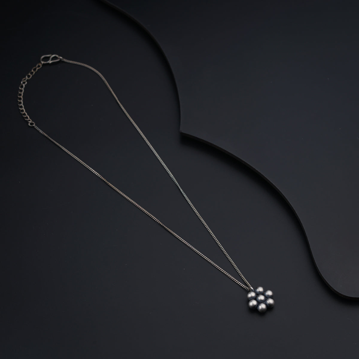 a necklace with a flower on a black background