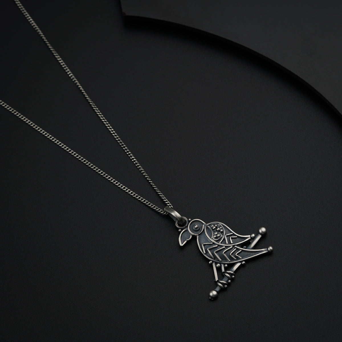 a silver necklace with a bird on it