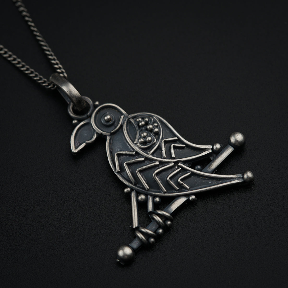 a black and silver necklace with a bird on it