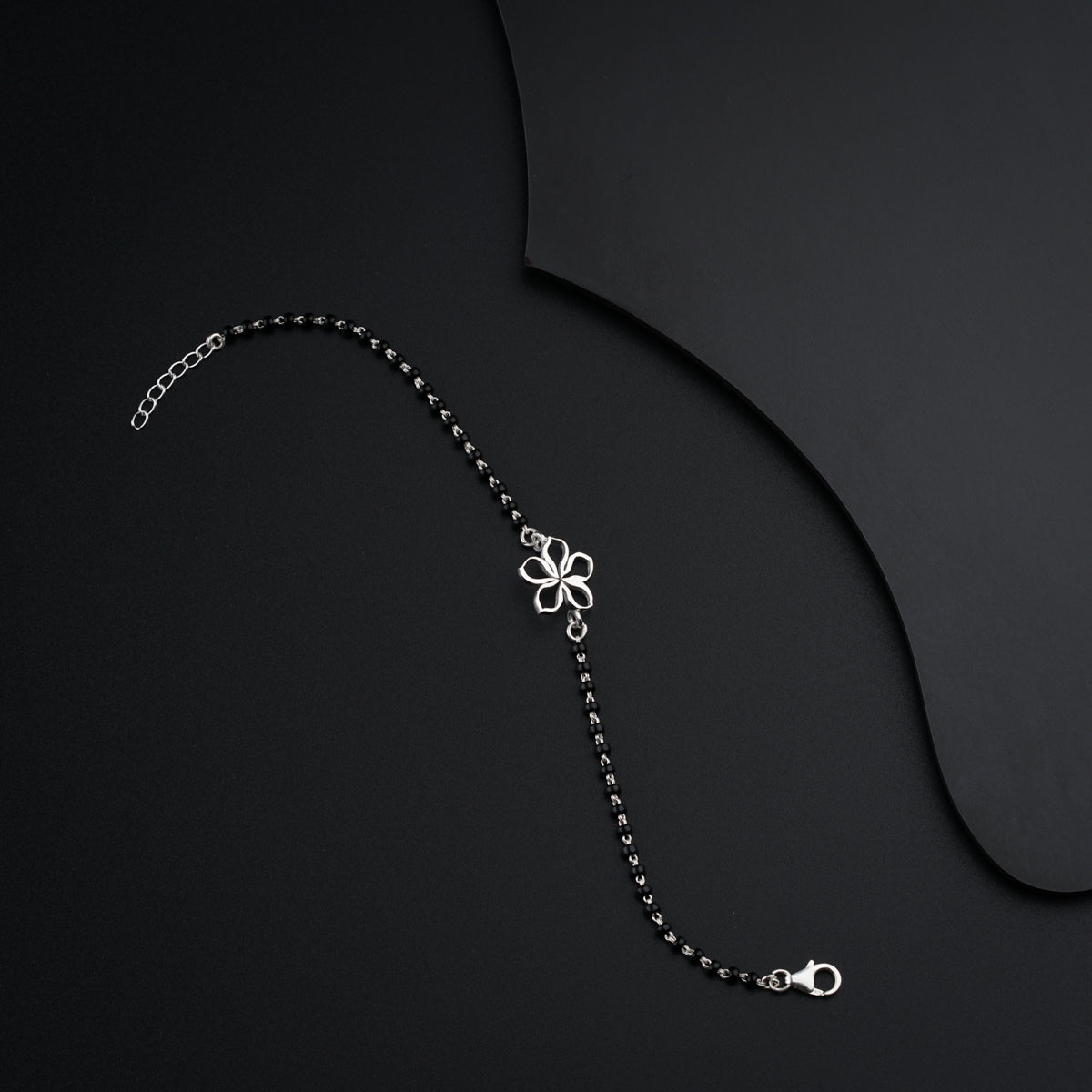 a chain with a flower on it on a black surface