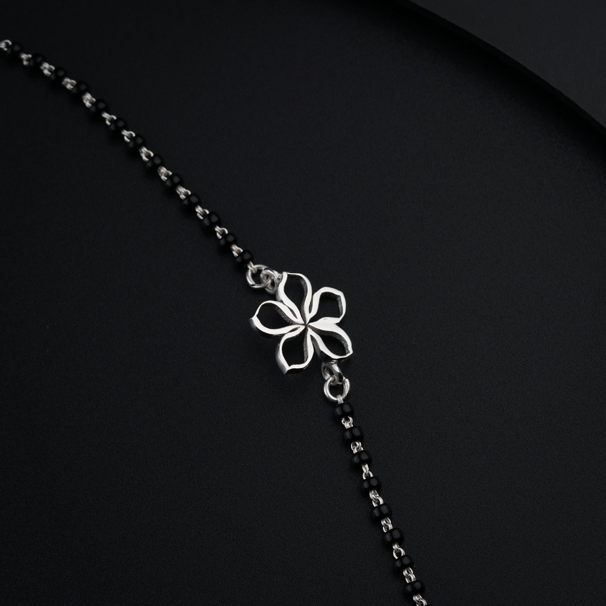 a chain with a flower on it on a black surface