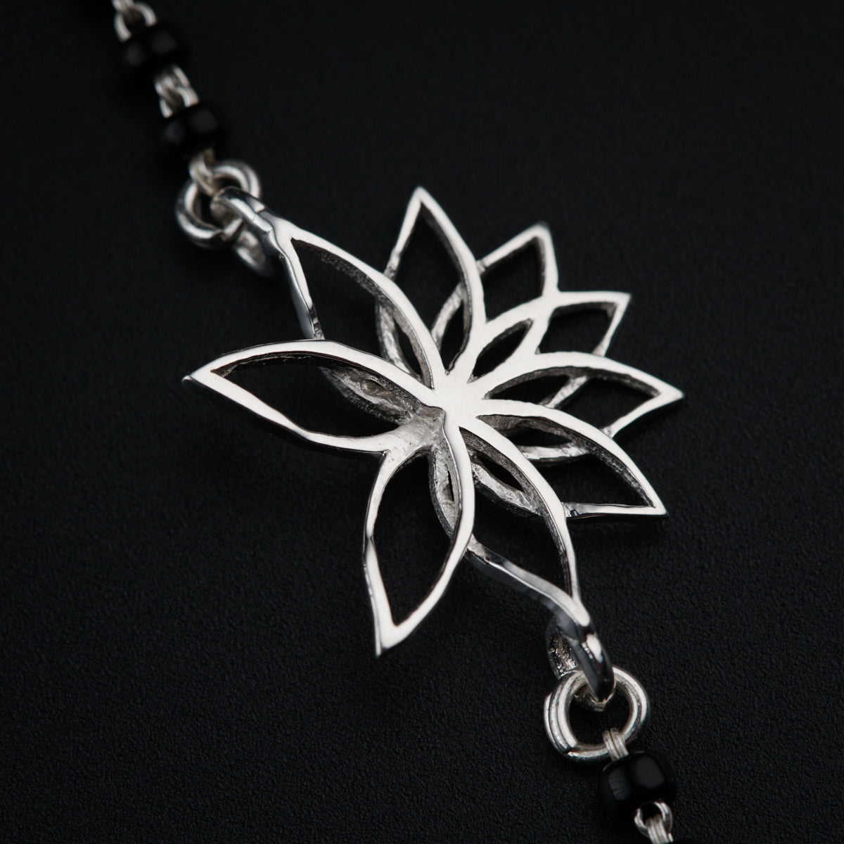 a silver flower on a chain on a black background