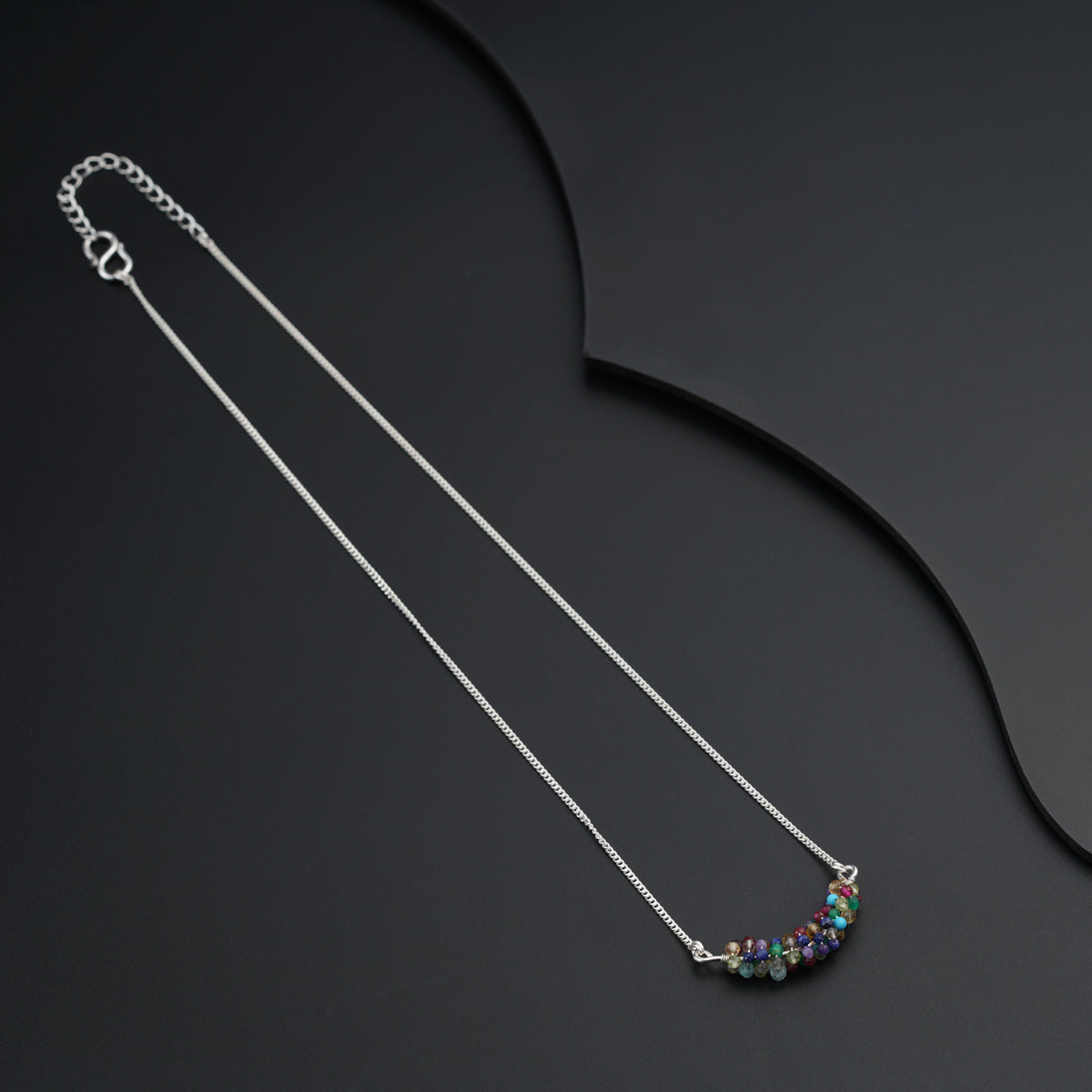 a silver chain with a multi colored bead on it