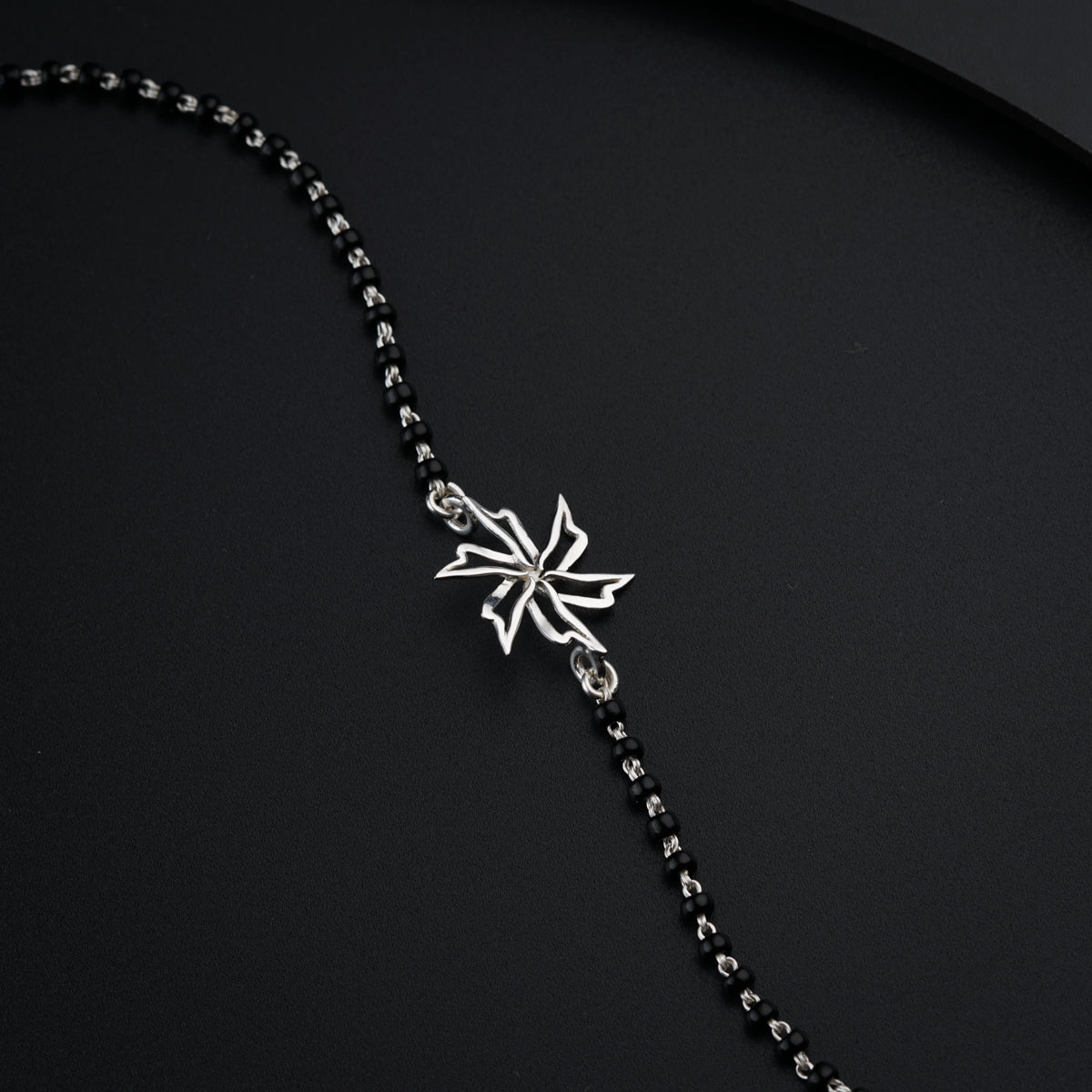 a black and silver necklace with a snowflake on it