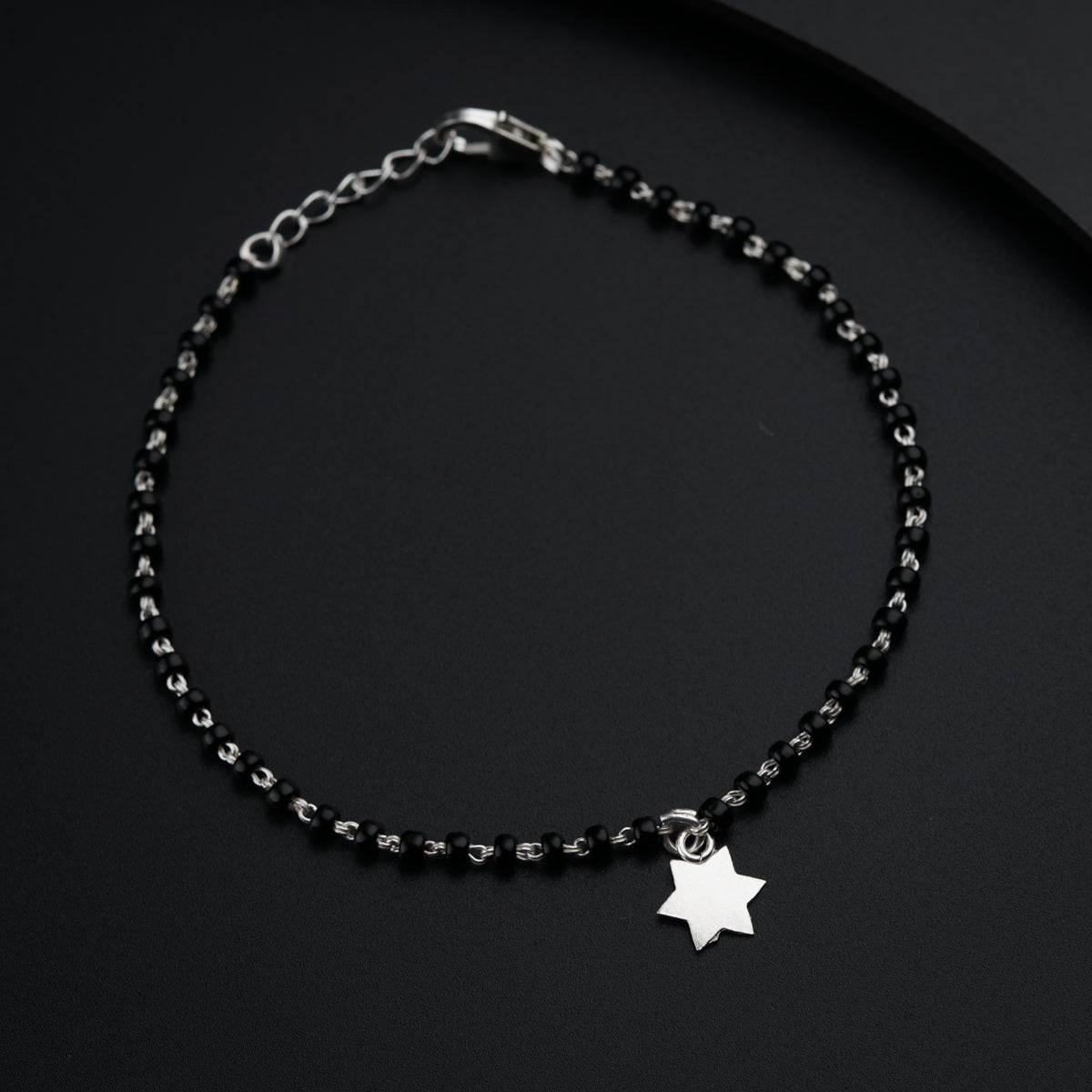 a black beaded bracelet with a silver star charm