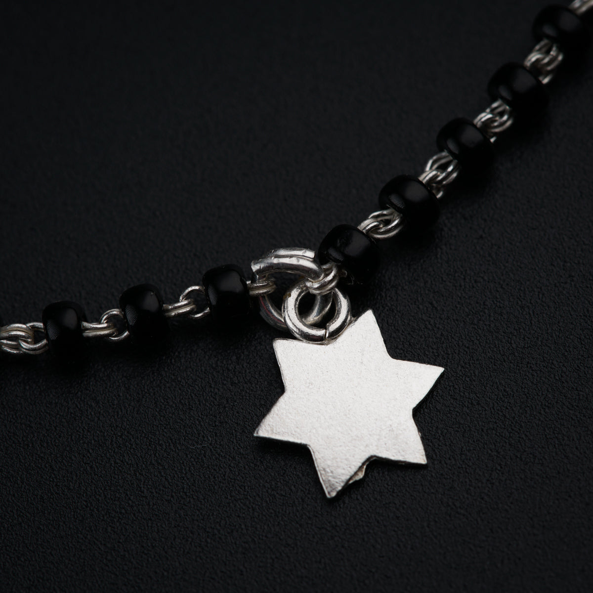 a silver star of david on a black beaded chain