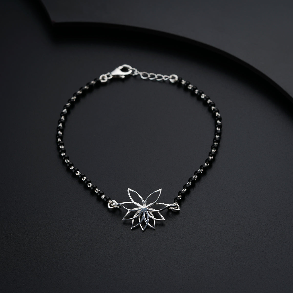 a black beaded bracelet with a flower charm