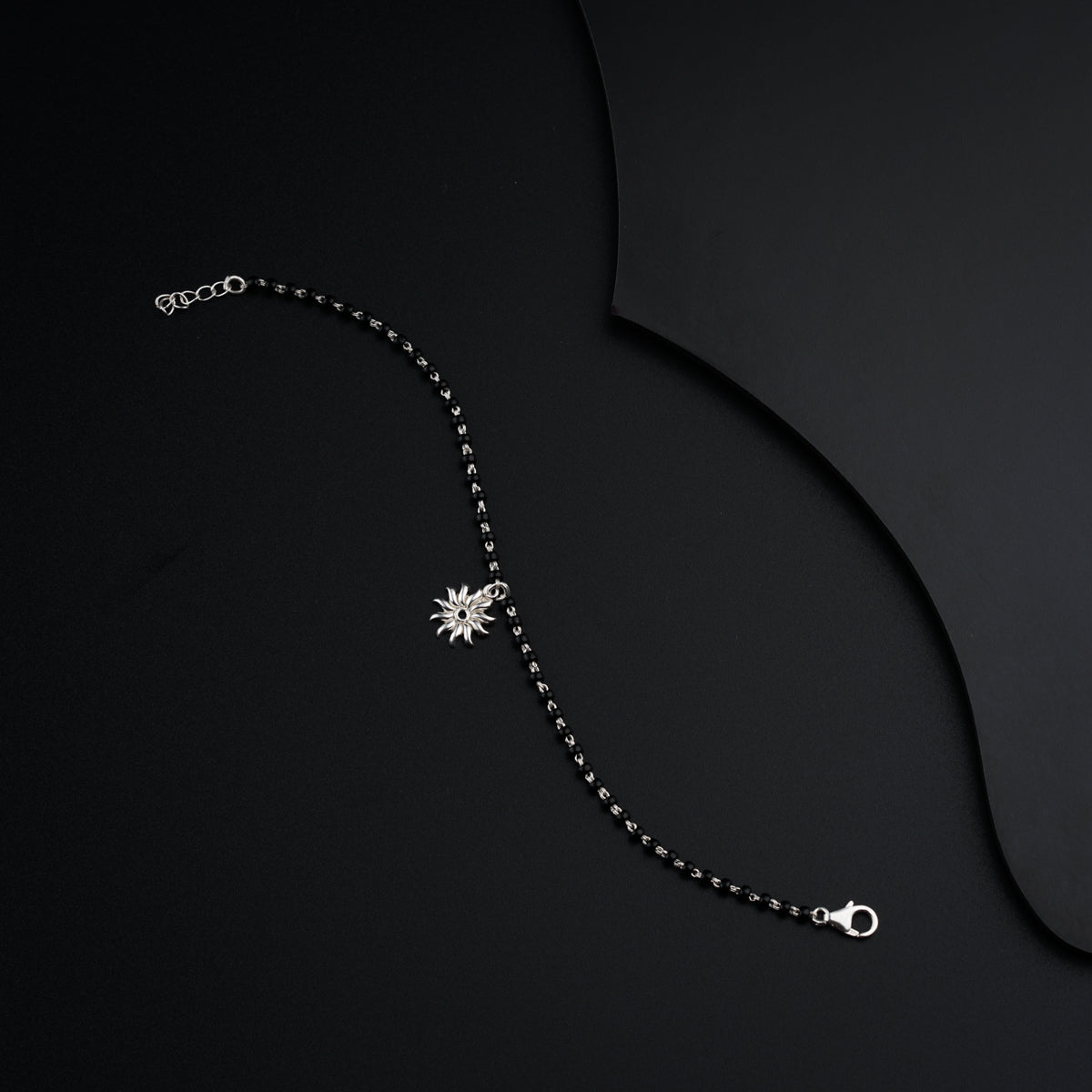 a black background with a silver chain and a star pendant