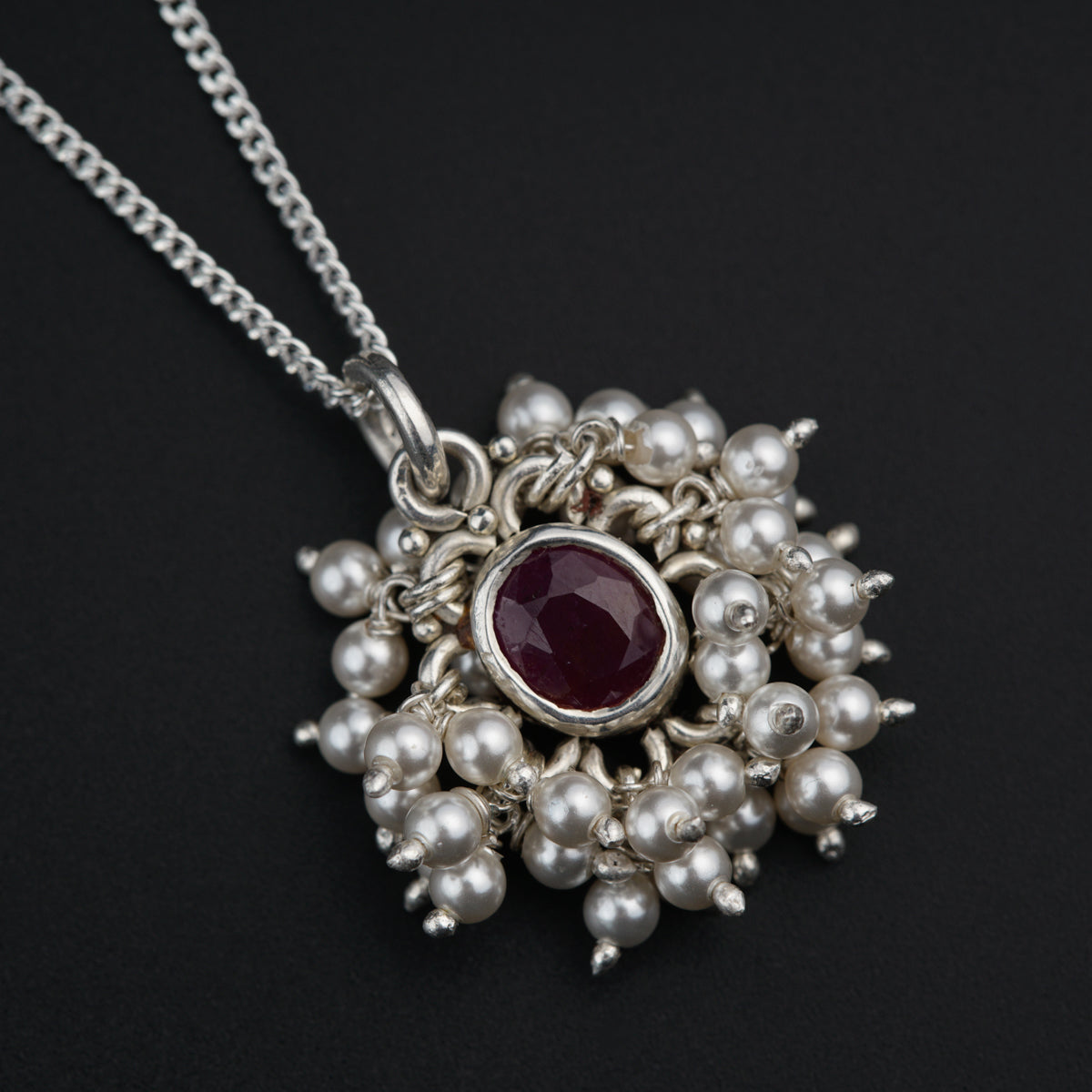 a necklace with a red stone surrounded by pearls