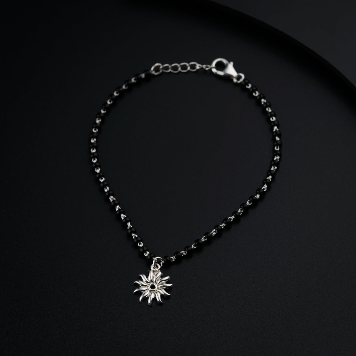 a black beaded bracelet with a silver star charm