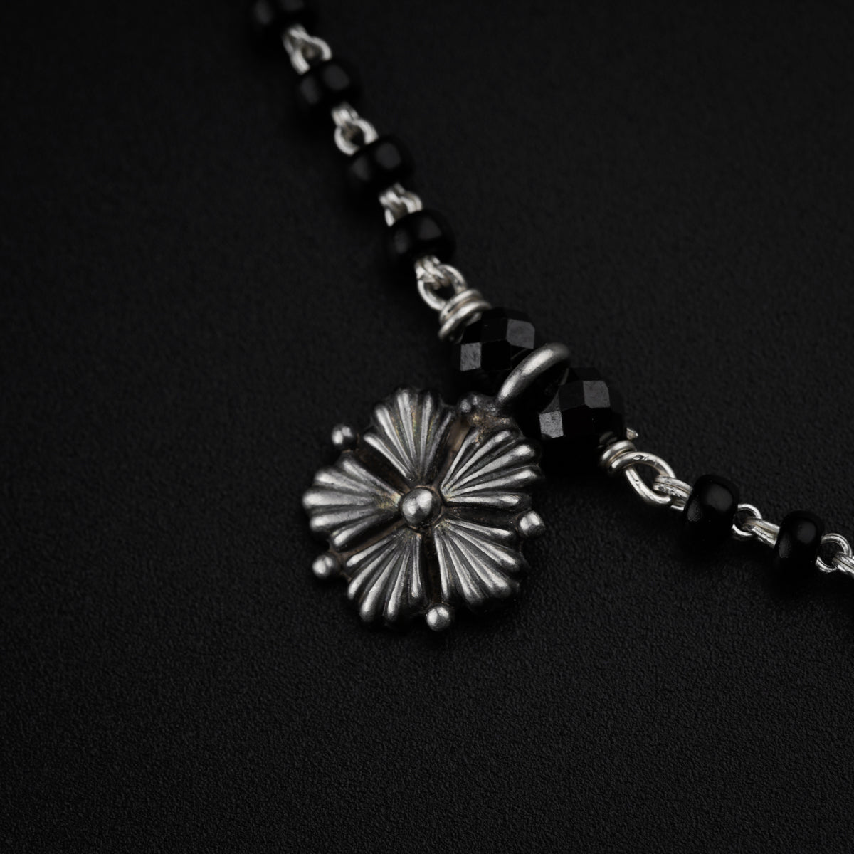 a black and silver necklace with a flower on it