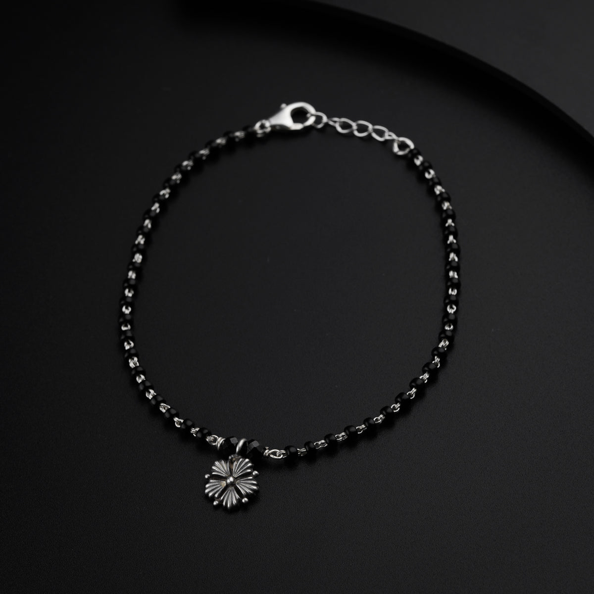 a black beaded bracelet with a flower charm