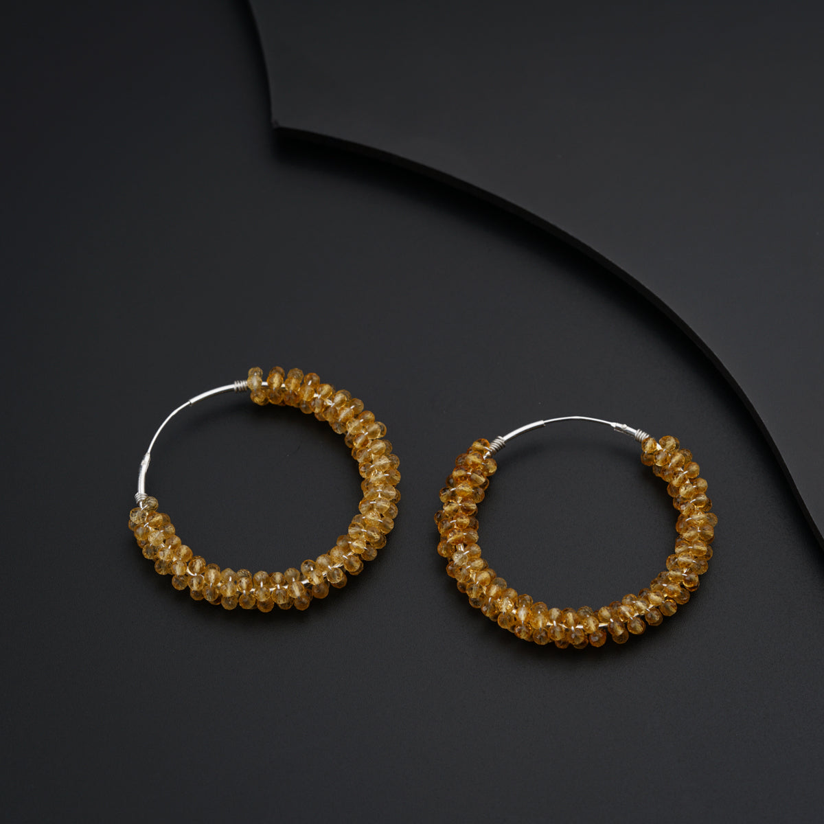a pair of gold hoop earrings on a black surface