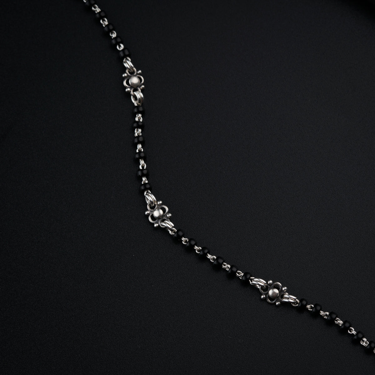 a black and silver necklace on a black surface