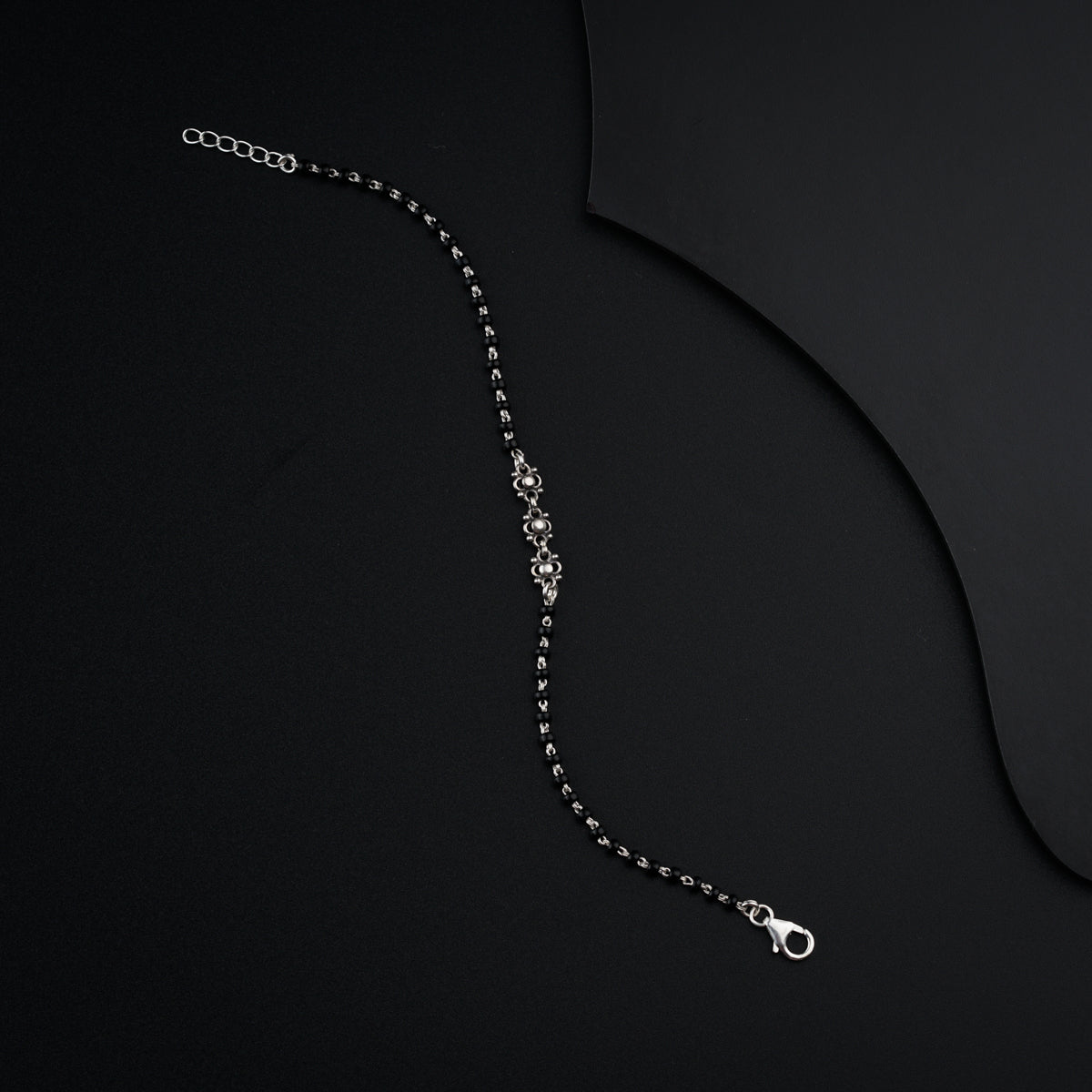 a black and white photo of a necklace on a black background