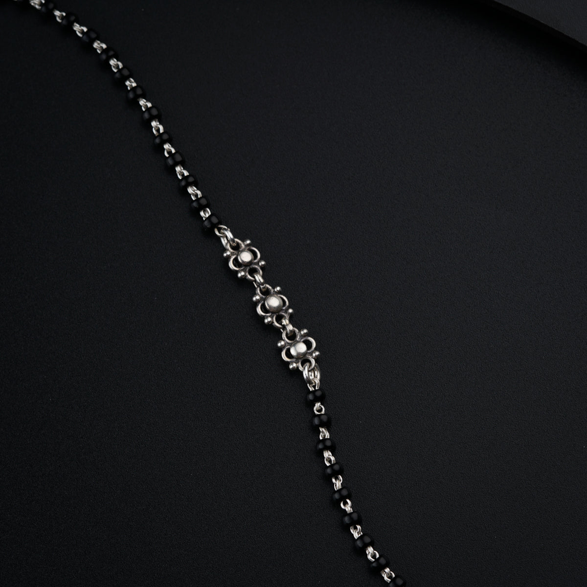 a black and silver necklace on a black surface