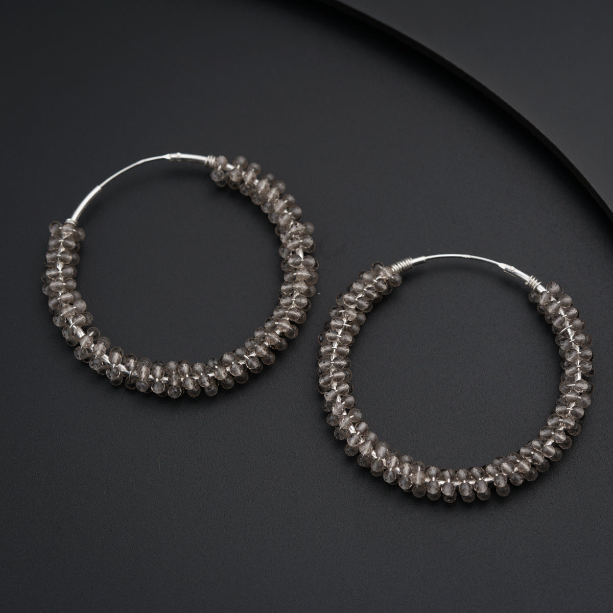 a pair of hoop earrings on a black surface