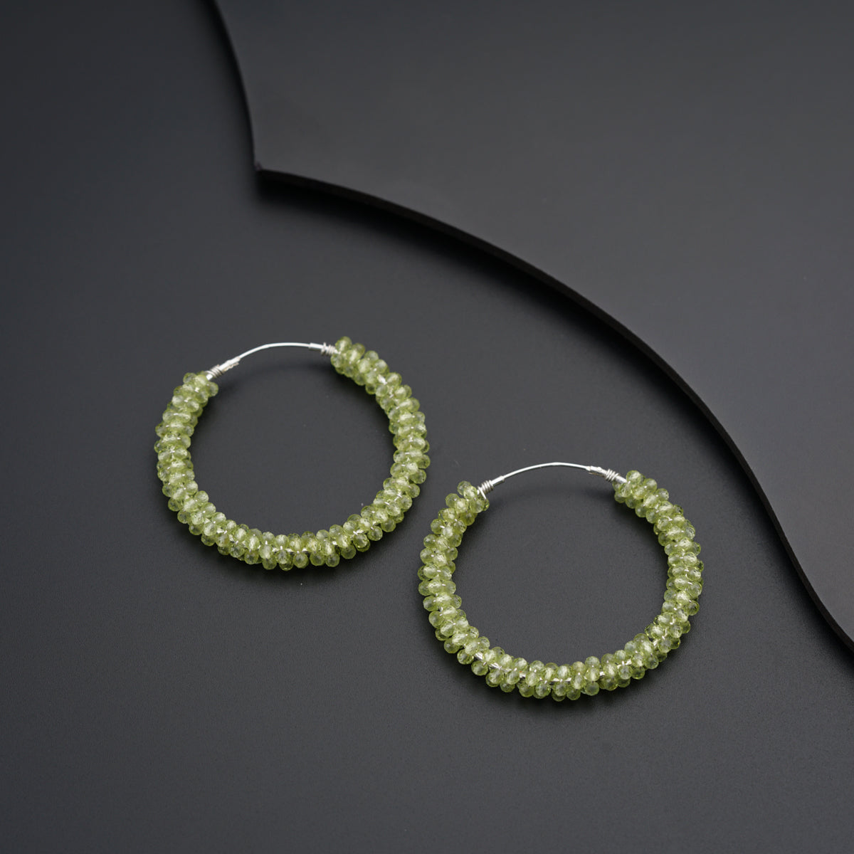 a pair of green beaded hoop earrings