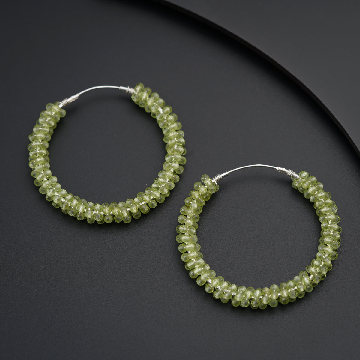 a pair of green beaded hoop earrings