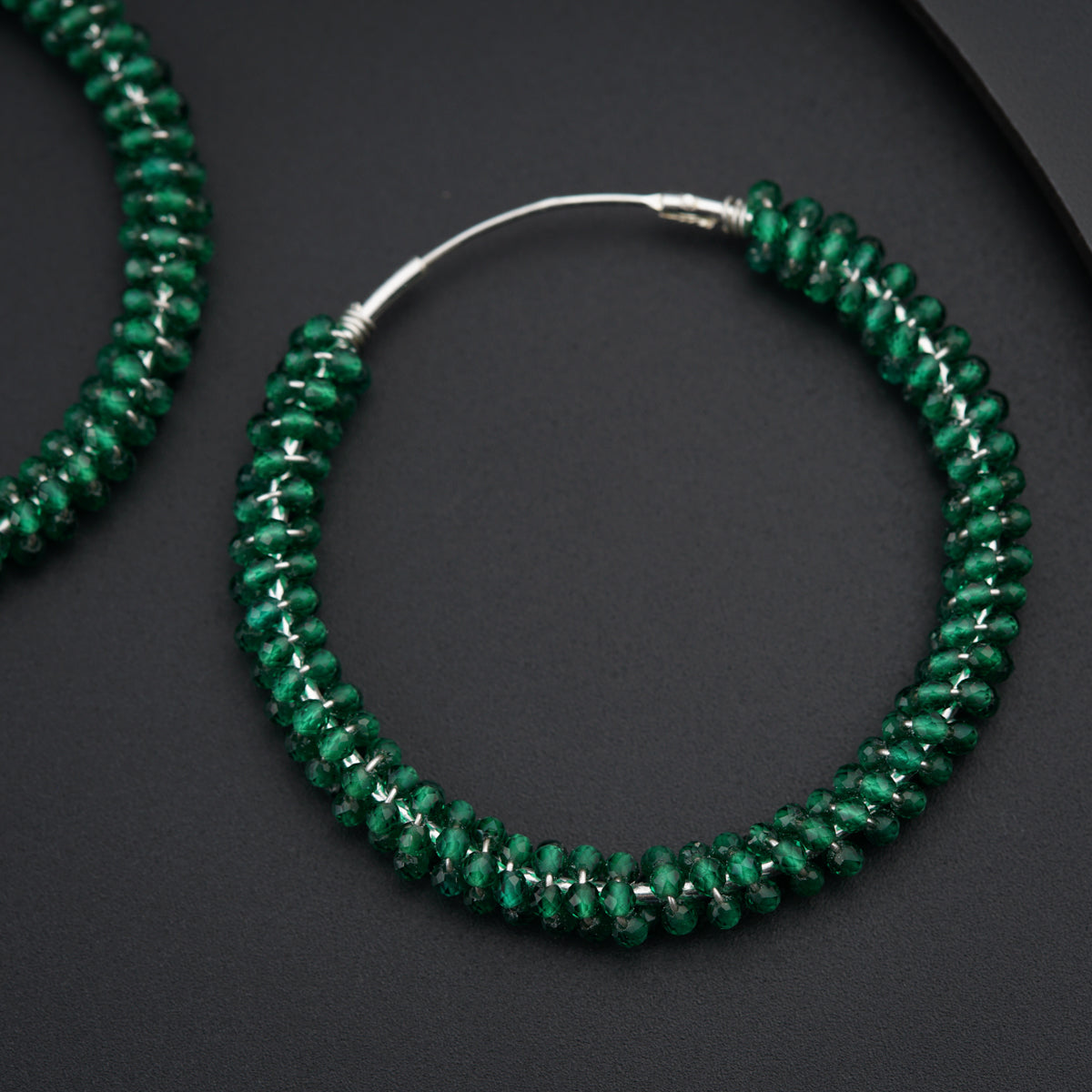 a pair of green beaded hoop earrings