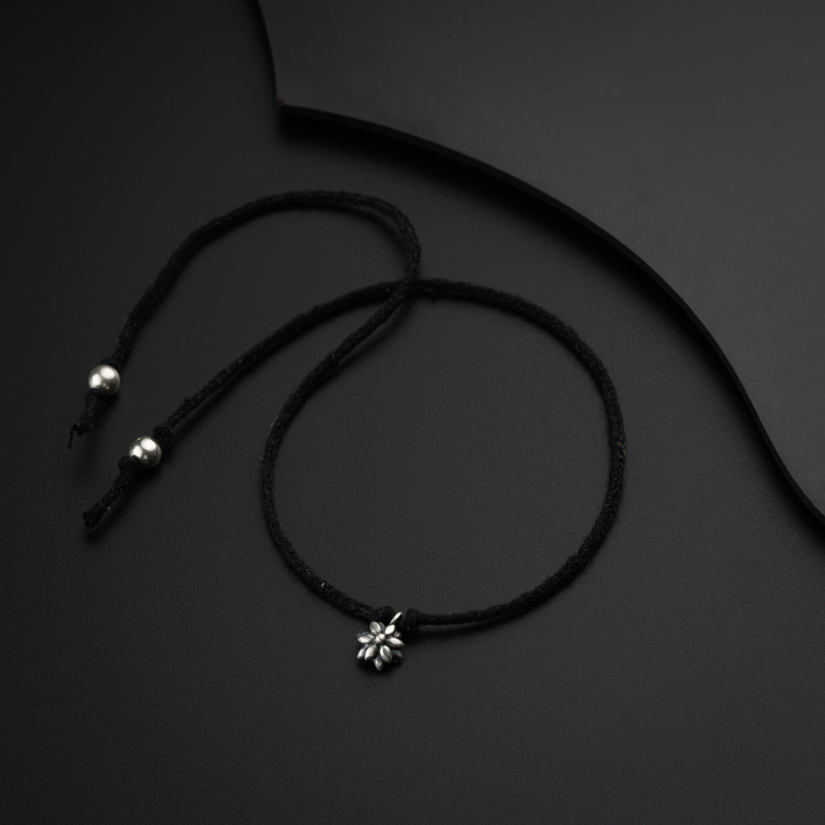 a black cord with a silver flower on it