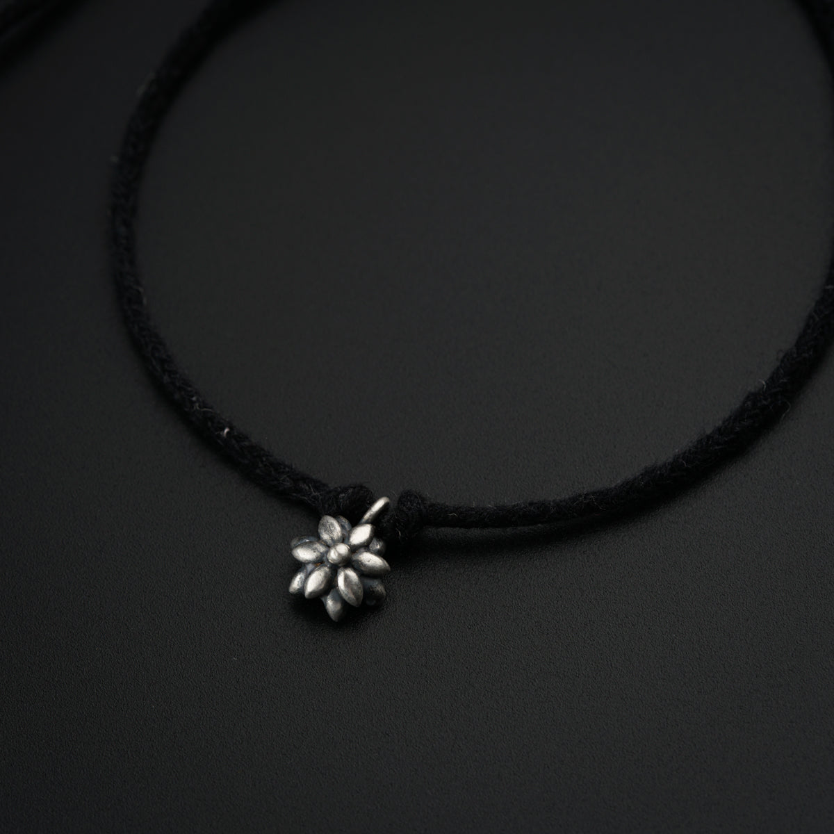a black cord necklace with a flower charm