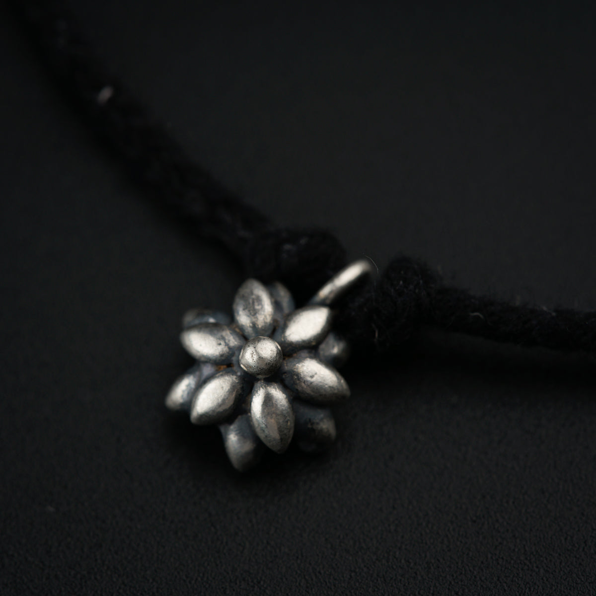 a black cord with a silver flower on it