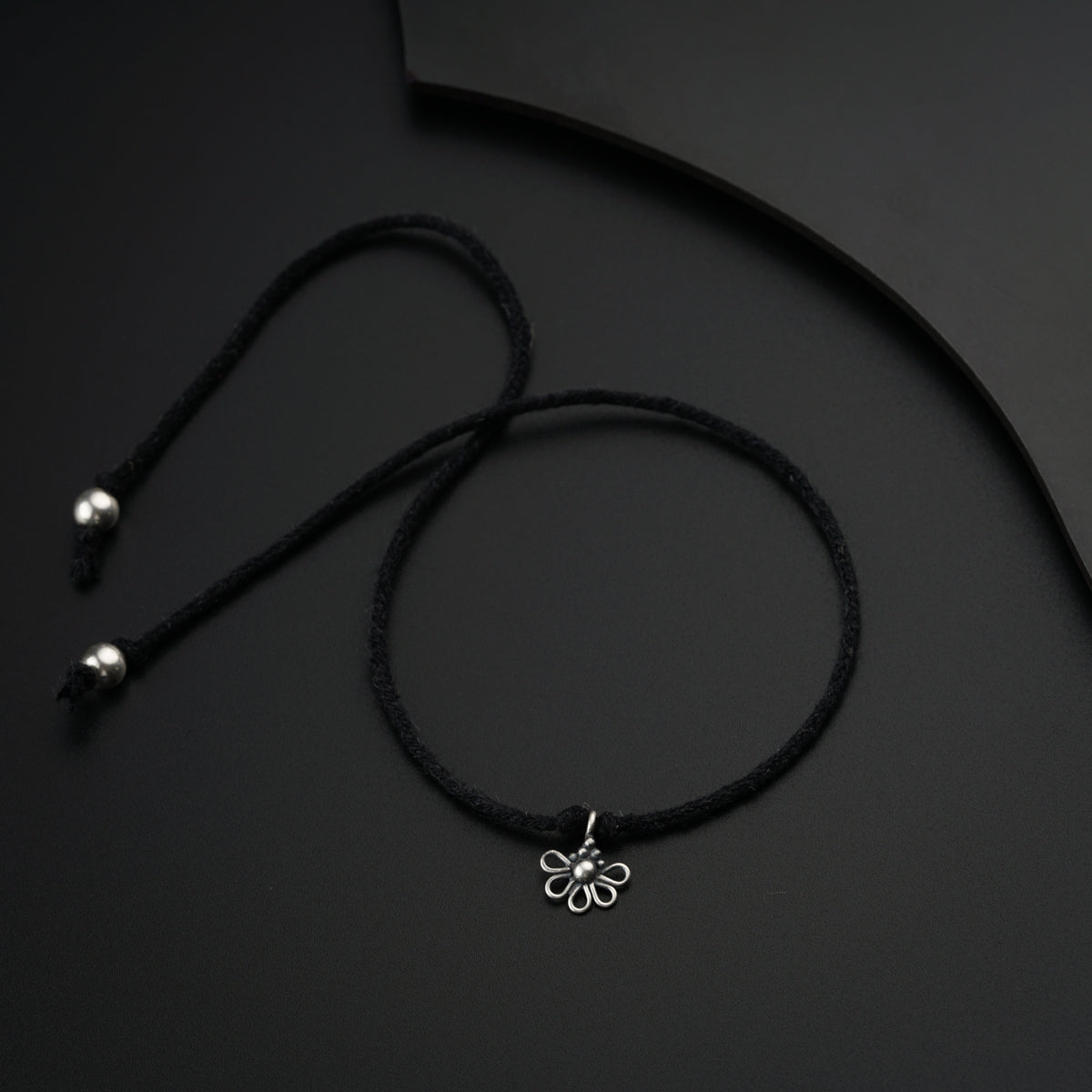 a black cord with a silver flower charm