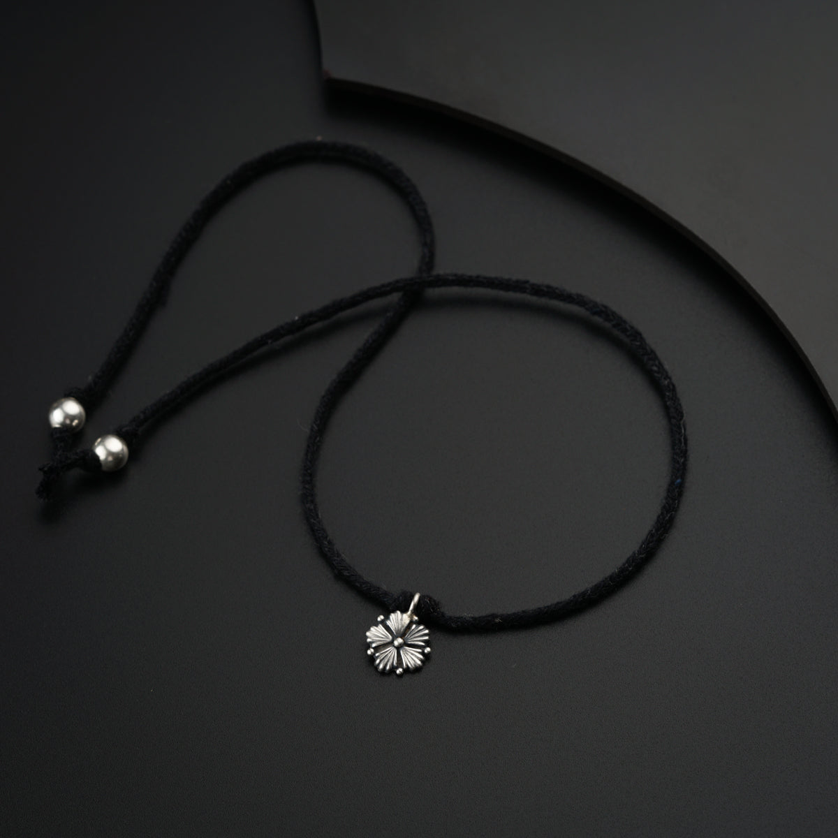 a necklace with a flower on a black background