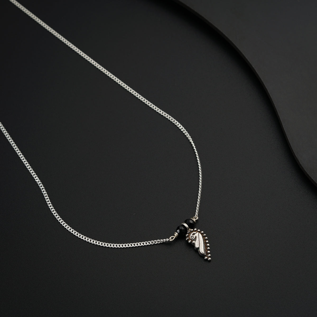 a silver necklace with a bird on it