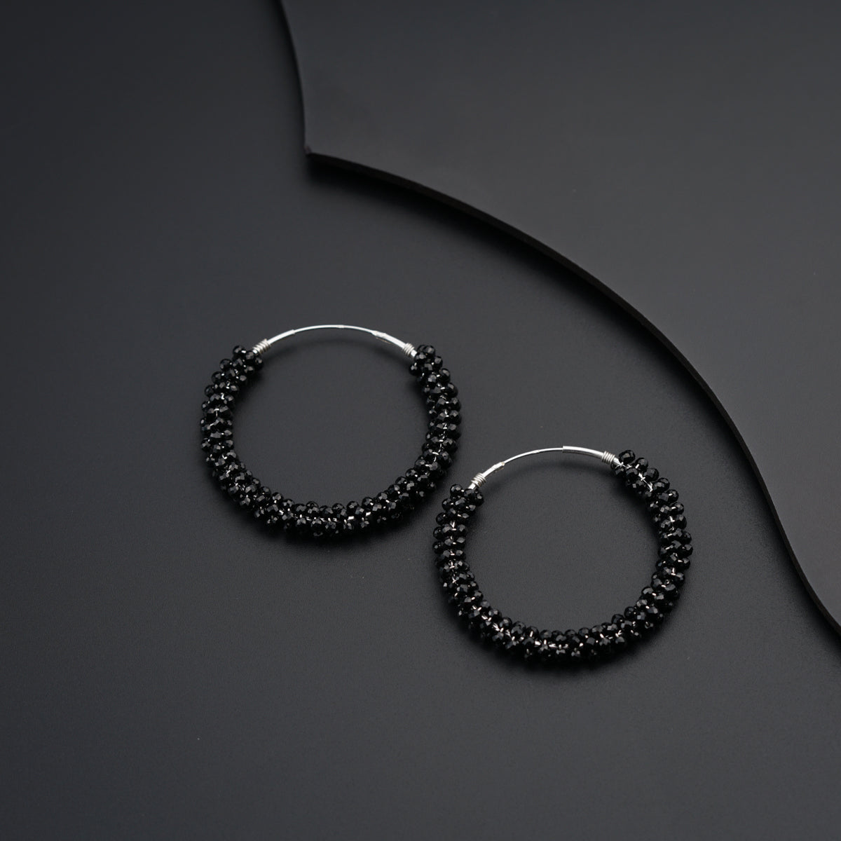 a pair of black beaded hoop earrings