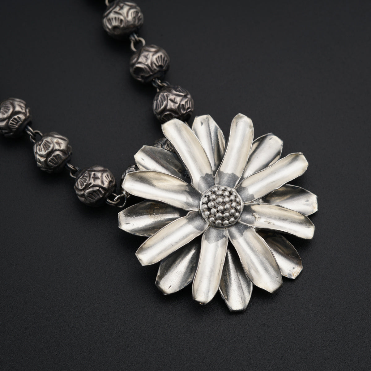 a silver necklace with a flower and skulls on it