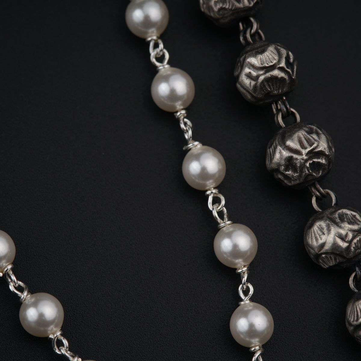 a rosary with skulls and pearls on a black background