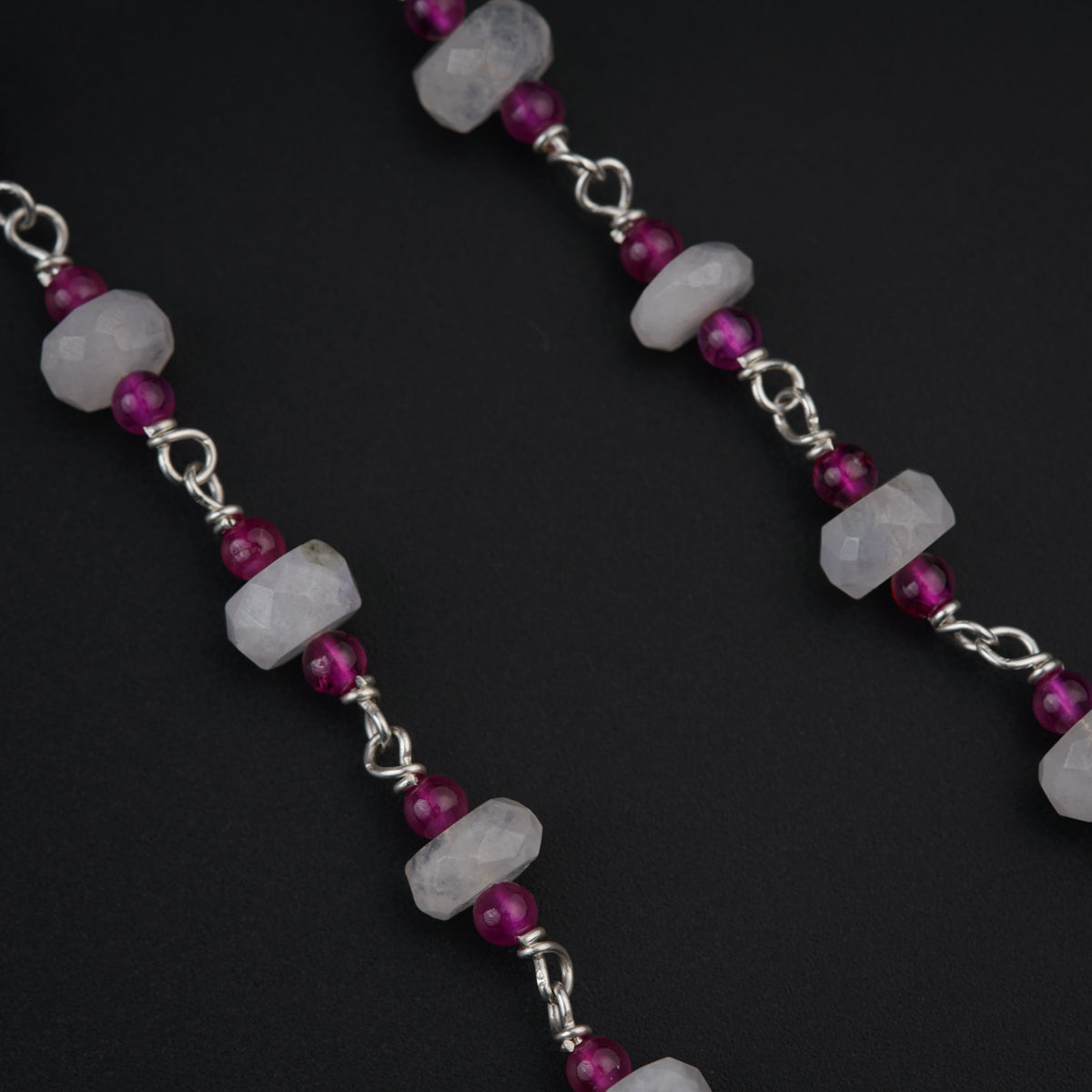 a pair of silver and pink beads on a black background