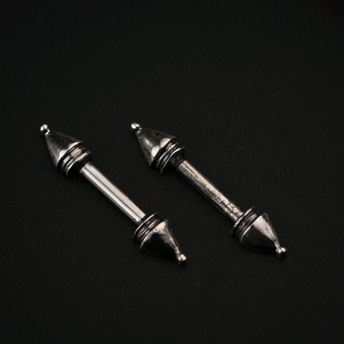 a pair of silver colored screws on a black background