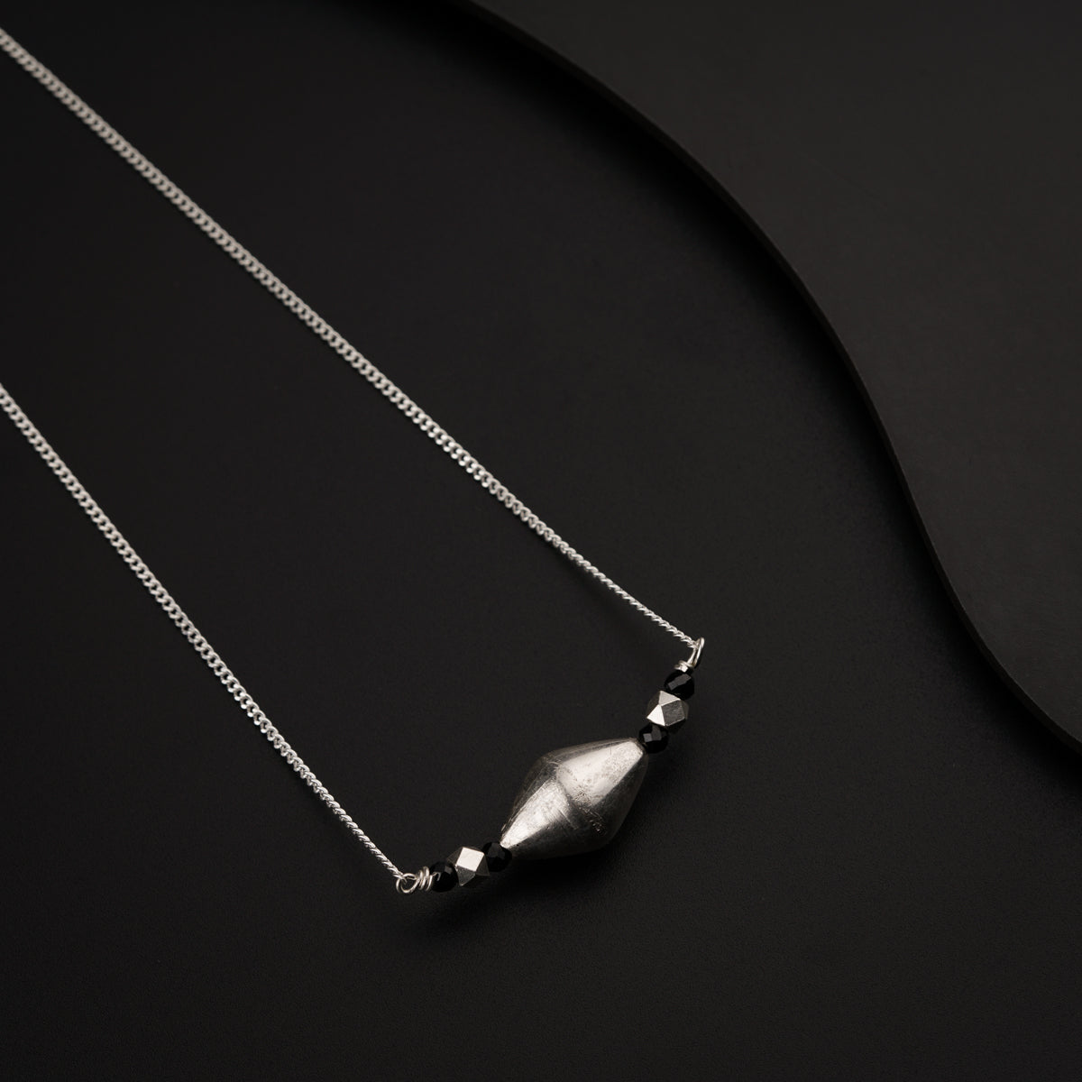 a necklace with a bottle on a black surface